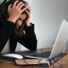 woman in black long sleeve shirt covering her face with her hands