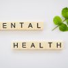 the word mental health spelled with scrabbles next to a green leaf