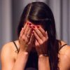 woman in black tank top covering her face with her hands