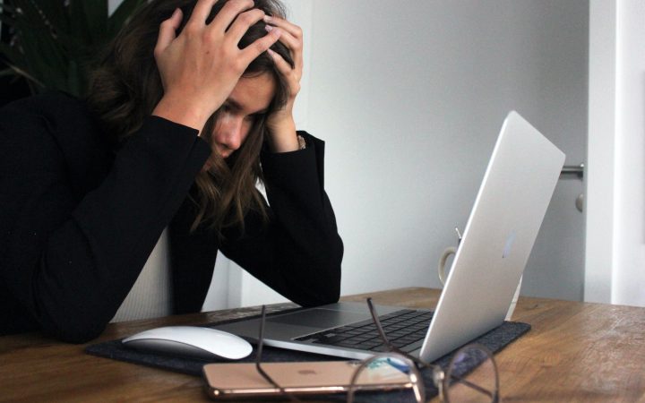 woman in black long sleeve shirt covering her face with her hands