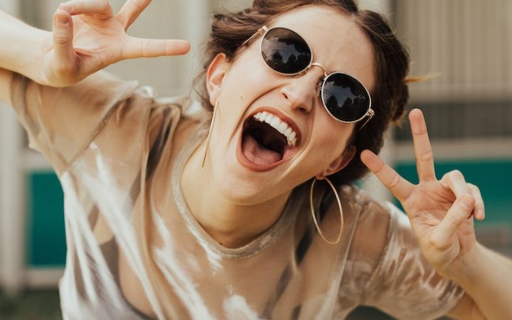 selective focus photography of jolly woman using peace hand gesture