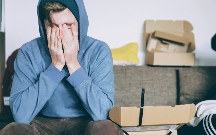 man covering face with both hands while sitting on bench